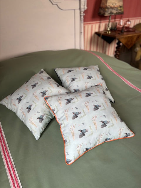 Coussin vert d'eau à passepoil orange fluo